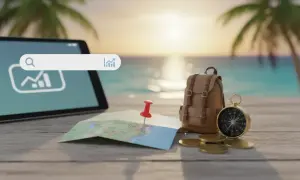 Tablet z wyszukiwarką, mapa, plecak, kompas i monety na tle plaży.